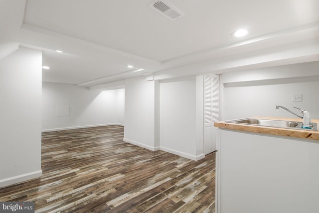 basement with dark hardwood / wood-style flooring and sink