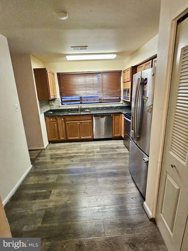 kitchen featuring dark hardwood / wood-style flooring, tasteful backsplash, a textured ceiling, stainless steel appliances, and sink