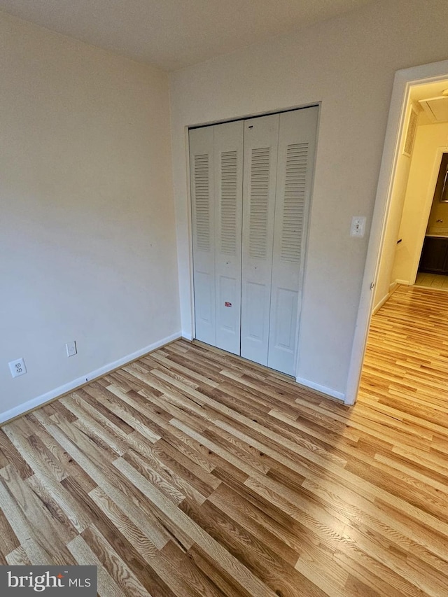 unfurnished bedroom with a closet and light hardwood / wood-style floors