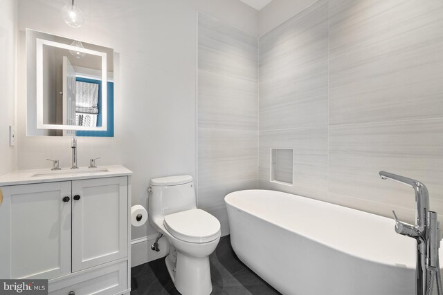 bathroom with a tub, vanity, tile walls, and toilet