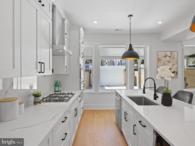 kitchen featuring appliances with stainless steel finishes, light hardwood / wood-style floors, white cabinetry, and sink