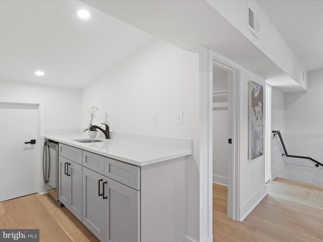 interior space featuring washer / dryer, light hardwood / wood-style floors, gray cabinetry, and sink