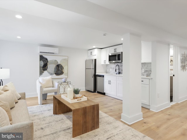 living room with sink, light hardwood / wood-style floors, and a wall mounted air conditioner