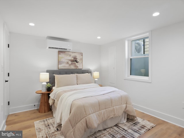 bedroom featuring light hardwood / wood-style floors and a wall unit AC