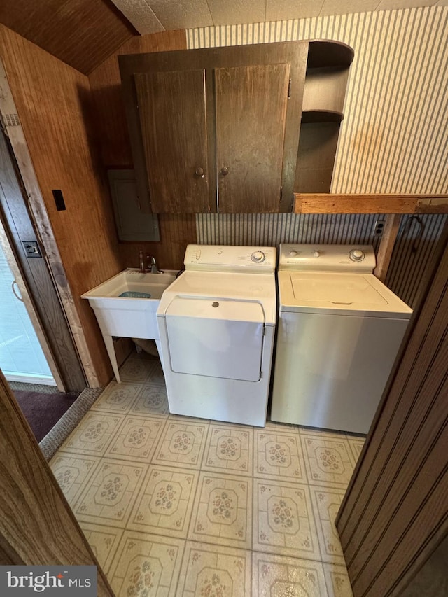 clothes washing area featuring wood walls, cabinets, sink, and washing machine and clothes dryer