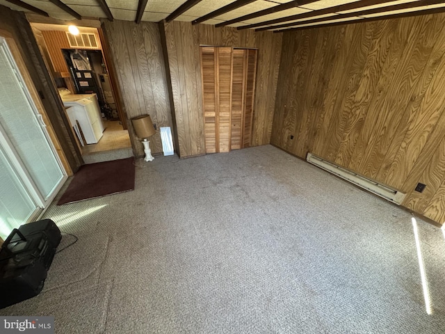 interior space featuring carpet, washer / clothes dryer, a baseboard heating unit, and wood walls