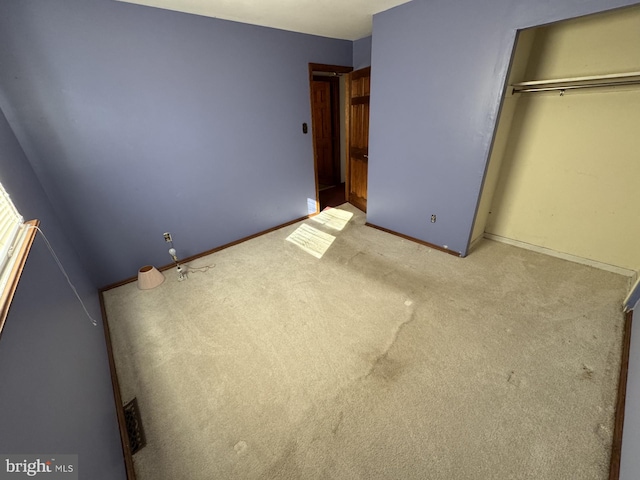 unfurnished bedroom featuring light carpet and a closet