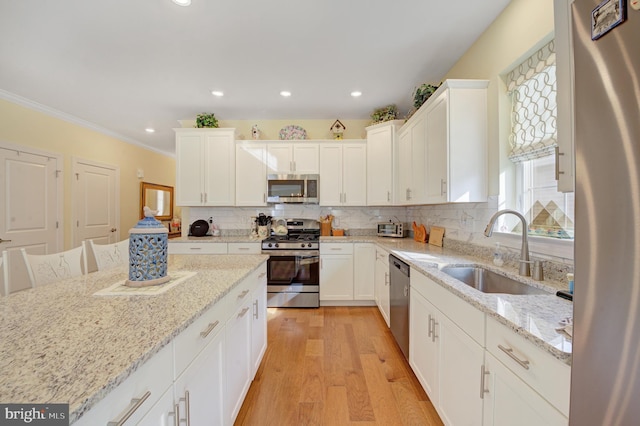 kitchen featuring crown molding, sink, light wood-type flooring, appliances with stainless steel finishes, and light stone counters