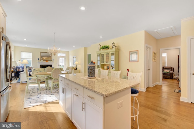 kitchen with white cabinets, a breakfast bar, a center island, and light wood-type flooring