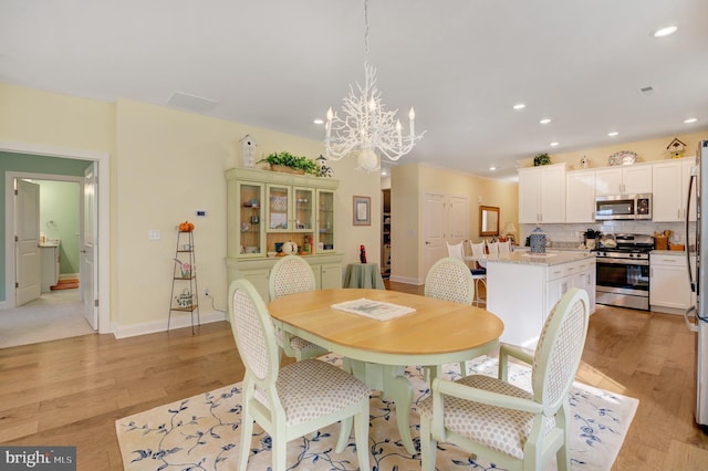 dining space featuring an inviting chandelier and light hardwood / wood-style flooring