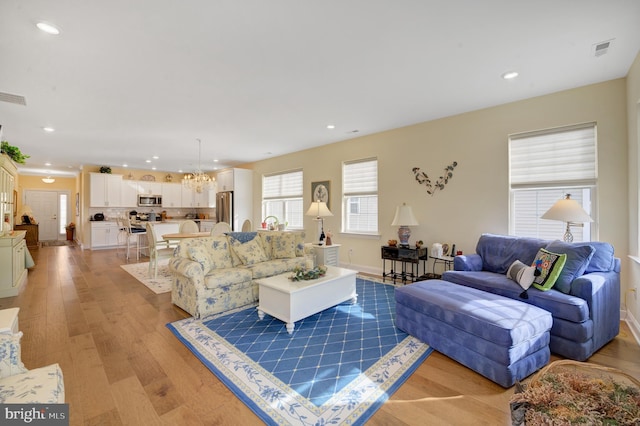 living room with light hardwood / wood-style flooring and an inviting chandelier