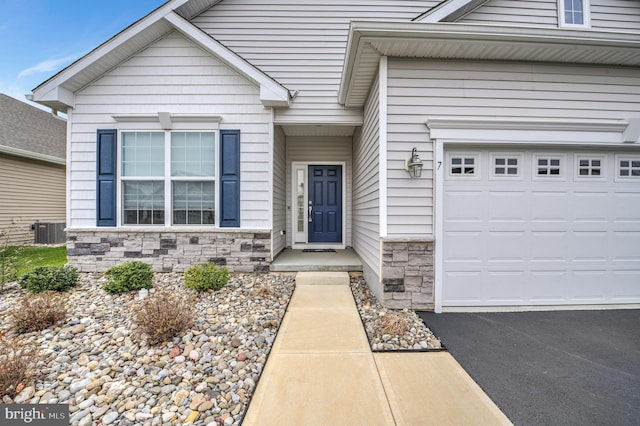 view of exterior entry with central air condition unit and a garage