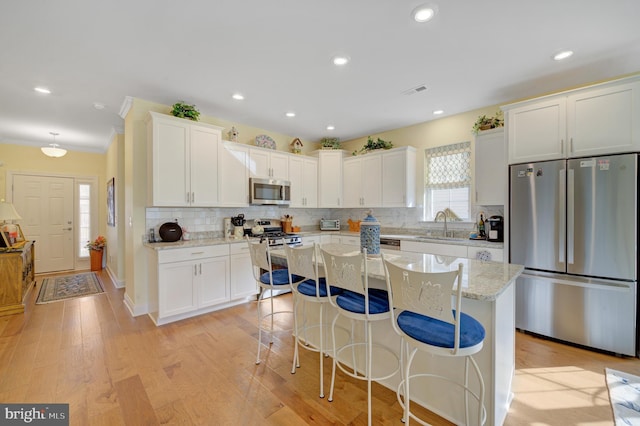 kitchen featuring white cabinetry, light hardwood / wood-style flooring, a center island, and appliances with stainless steel finishes