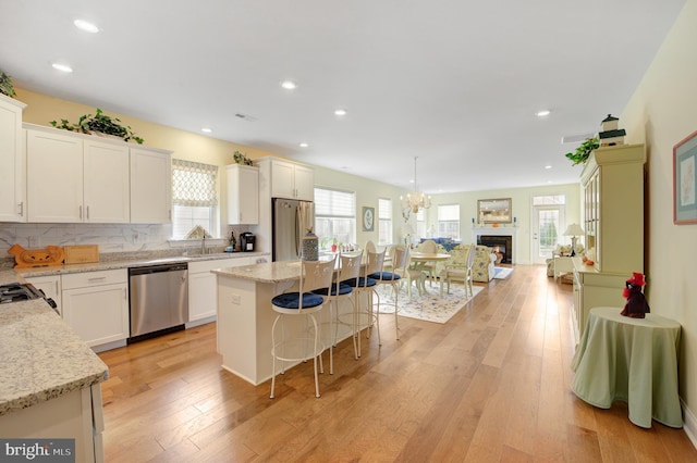 kitchen with white cabinetry, light hardwood / wood-style flooring, a kitchen island, and stainless steel appliances