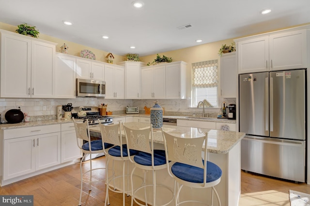 kitchen featuring appliances with stainless steel finishes, a center island, white cabinetry, and sink