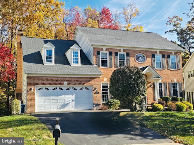 colonial inspired home with a garage and a front lawn