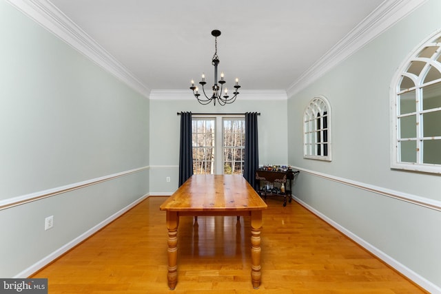 dining room featuring hardwood / wood-style flooring, crown molding, and an inviting chandelier