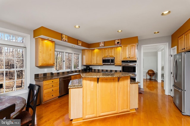 kitchen with appliances with stainless steel finishes, a center island, light hardwood / wood-style flooring, and a wealth of natural light