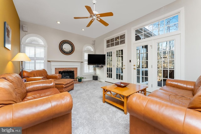 carpeted living room featuring ceiling fan, a fireplace, and a high ceiling