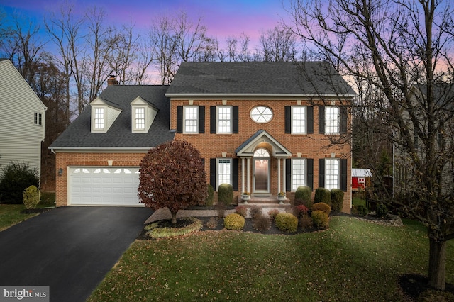 colonial-style house featuring a garage and a lawn