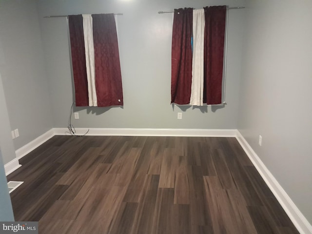 unfurnished room with dark wood-type flooring