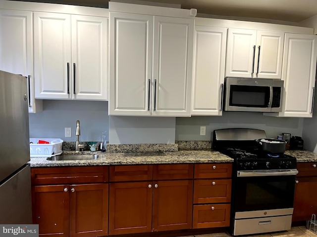 kitchen with light stone counters, sink, white cabinetry, and stainless steel appliances