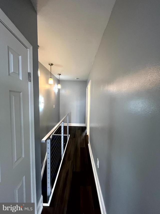 hall with an upstairs landing, dark wood-type flooring, and baseboards
