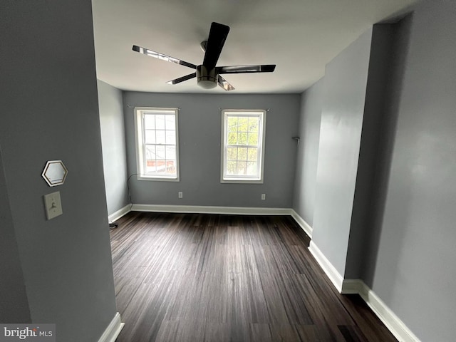 spare room featuring baseboards, a ceiling fan, and dark wood finished floors
