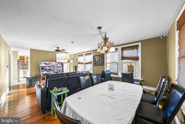 dining room featuring wood-type flooring and ceiling fan with notable chandelier