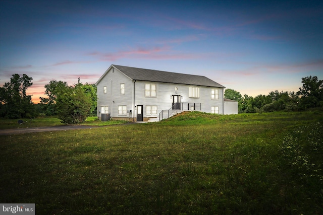 back house at dusk with cooling unit and a yard