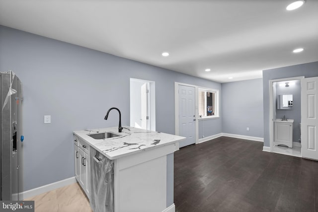 kitchen featuring light stone counters, sink, and dark wood-type flooring