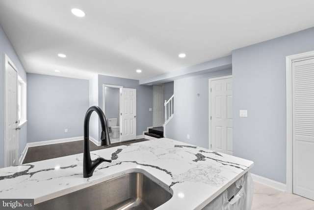 kitchen with light stone countertops, sink, and an island with sink