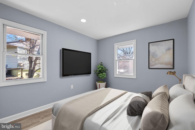 bedroom with multiple windows and hardwood / wood-style flooring