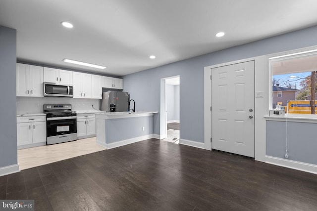 kitchen with white cabinets, dark hardwood / wood-style floors, and appliances with stainless steel finishes