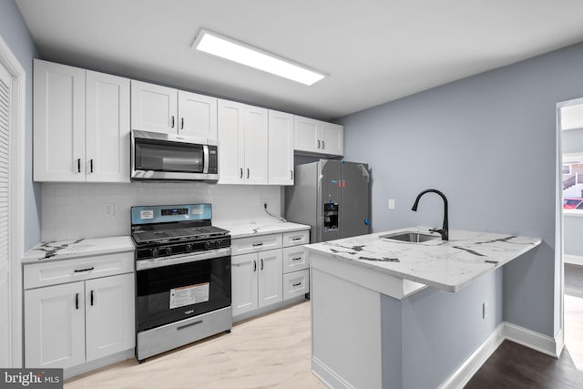 kitchen featuring sink, stainless steel appliances, light stone counters, decorative backsplash, and white cabinets