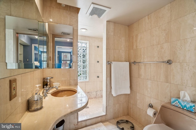 bathroom with sink, tasteful backsplash, tile patterned flooring, toilet, and tile walls