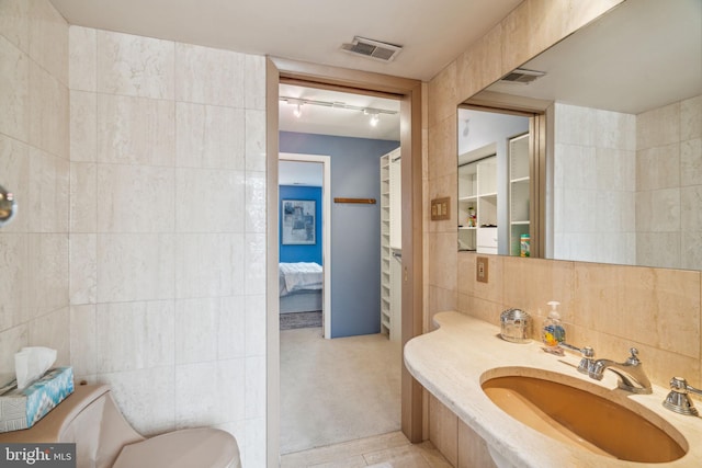 bathroom featuring sink, backsplash, tile patterned floors, toilet, and tile walls