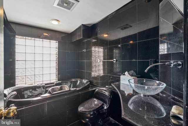 bathroom with tiled bath, sink, and tile walls