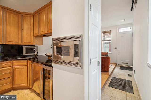 kitchen with wine cooler, stainless steel microwave, light tile patterned floors, and sink