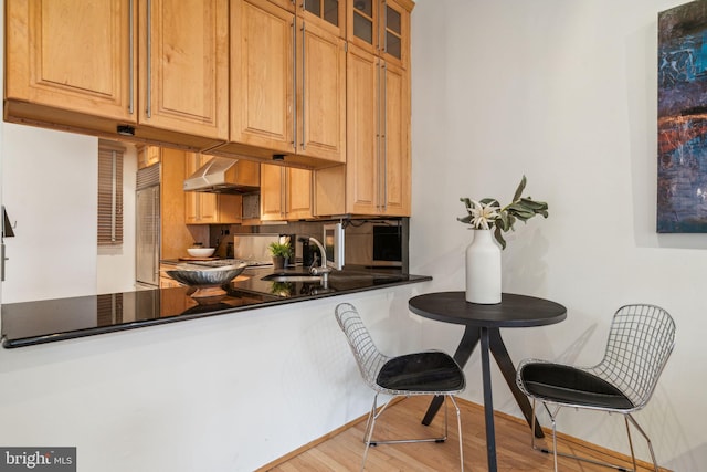 kitchen with exhaust hood, light wood-type flooring, built in fridge, and sink