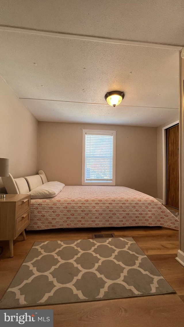 unfurnished bedroom with a textured ceiling and wood-type flooring