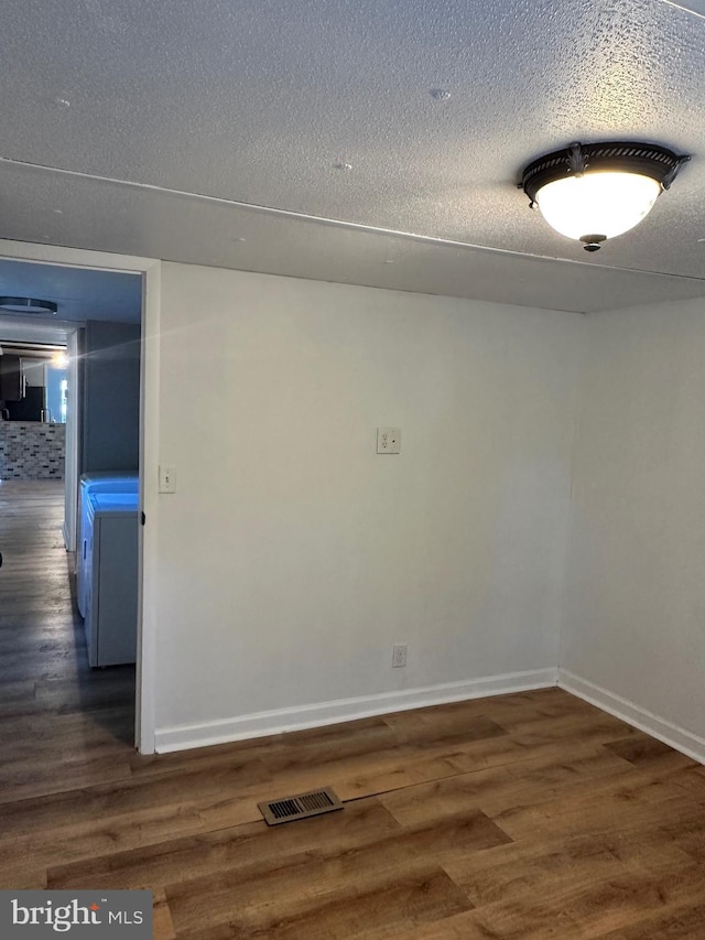 empty room with wood finished floors, a textured ceiling, and baseboards