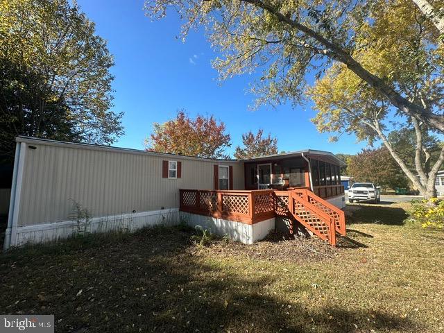 rear view of property with a deck, a yard, and a sunroom