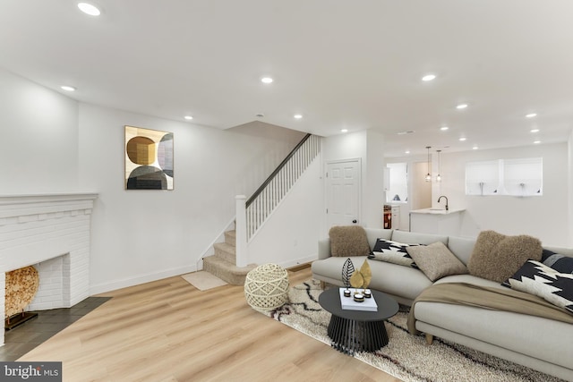 living room with hardwood / wood-style flooring, sink, and a fireplace