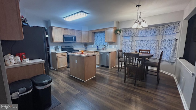 kitchen featuring appliances with stainless steel finishes, light brown cabinetry, a notable chandelier, a kitchen island, and hanging light fixtures