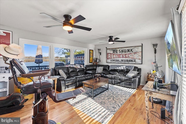 living room with ceiling fan, a water view, and hardwood / wood-style flooring