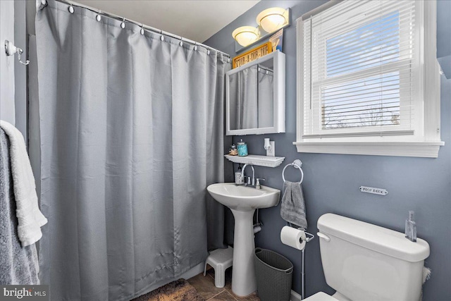 bathroom featuring a shower with curtain, sink, and toilet