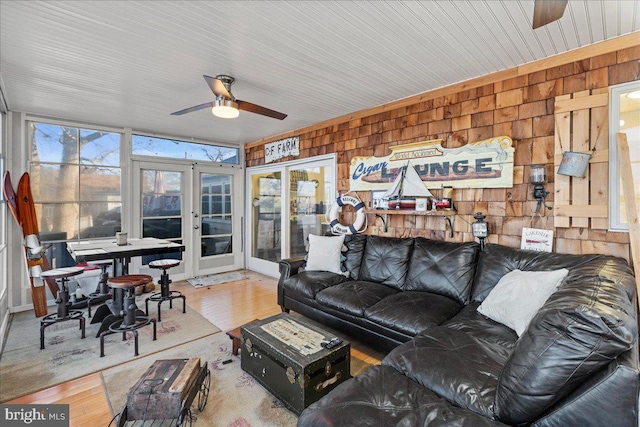 living room with french doors, hardwood / wood-style flooring, a wealth of natural light, and wooden walls