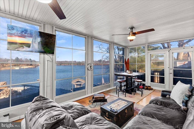 sunroom / solarium with french doors, a water view, plenty of natural light, and ceiling fan