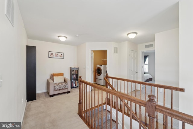 hallway featuring light colored carpet and washer and clothes dryer